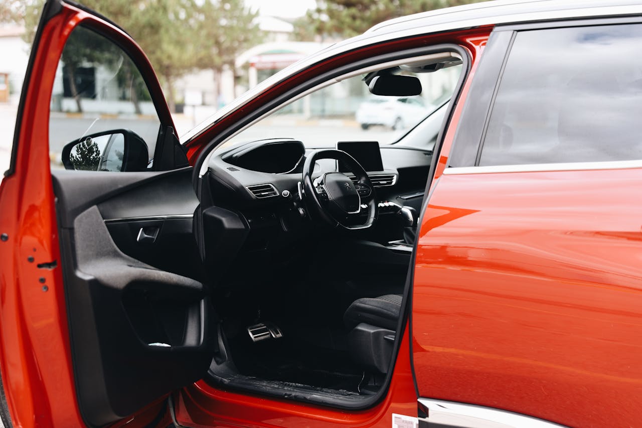 Open red car door revealing modern interior design parked outdoors in Sivas, Türkiye.