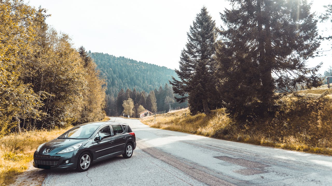 A black car on a beautiful autumn road through the forests of Grand Est, France.